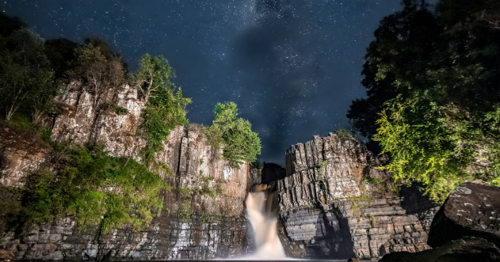 View of High Force Waterfall at night with a starry dark sky above